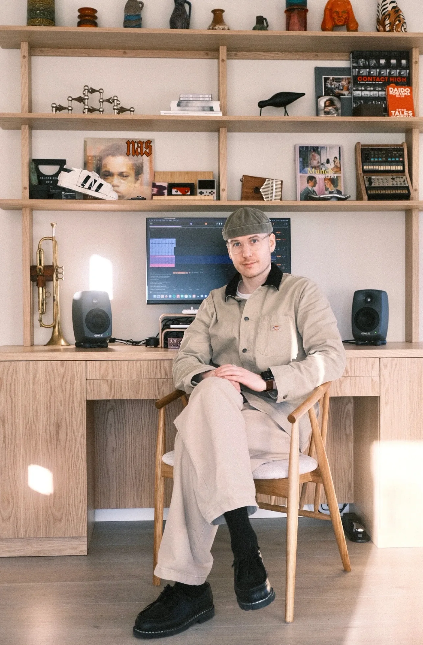 Kristoffer Eikrem sitting in his studio in Oslo, trumpet and Genelec monitors on the desk behind him