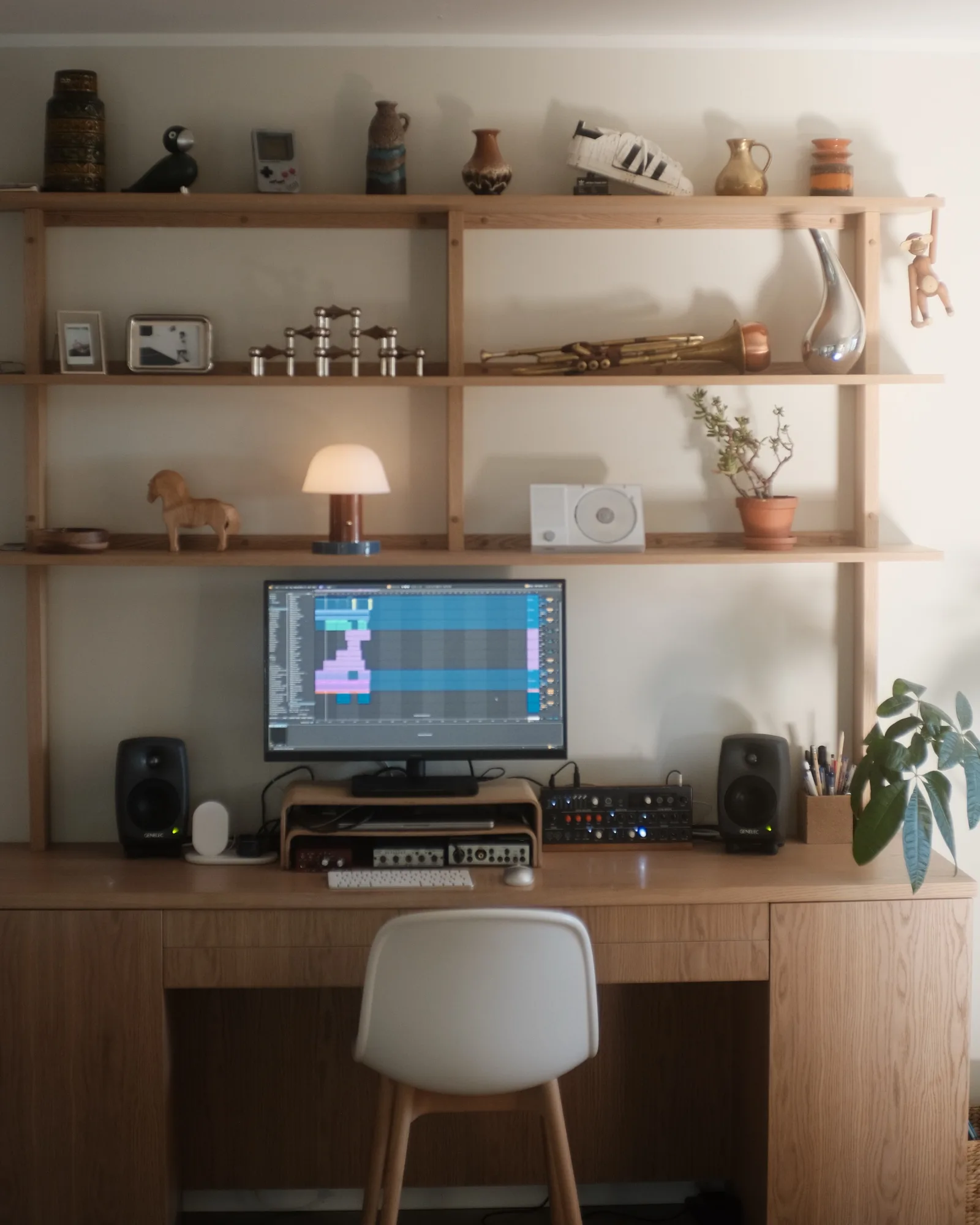 The oak desk and shelves: Genelec monitors, a screen with Ableton Live, ceramics, a lamp and a trumpet on the shelf