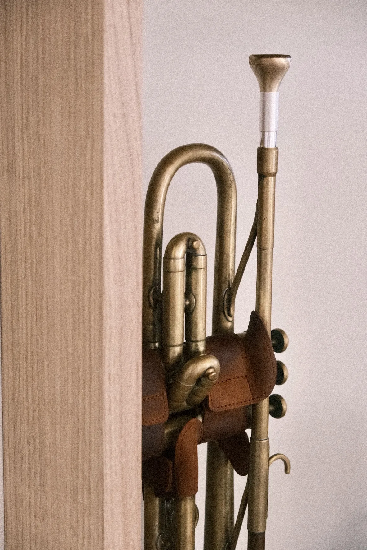 The 1947 Martin Committee trumpet with a leather valve guard, resting against the oak shelf